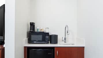 A compact kitchenette with a microwave, coffee maker, and sink.
