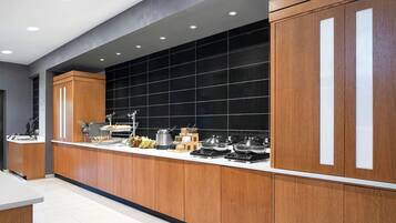 Une cuisine moderne avec des meubles en bois, un plan de travail noir et divers appareils de cuisson.