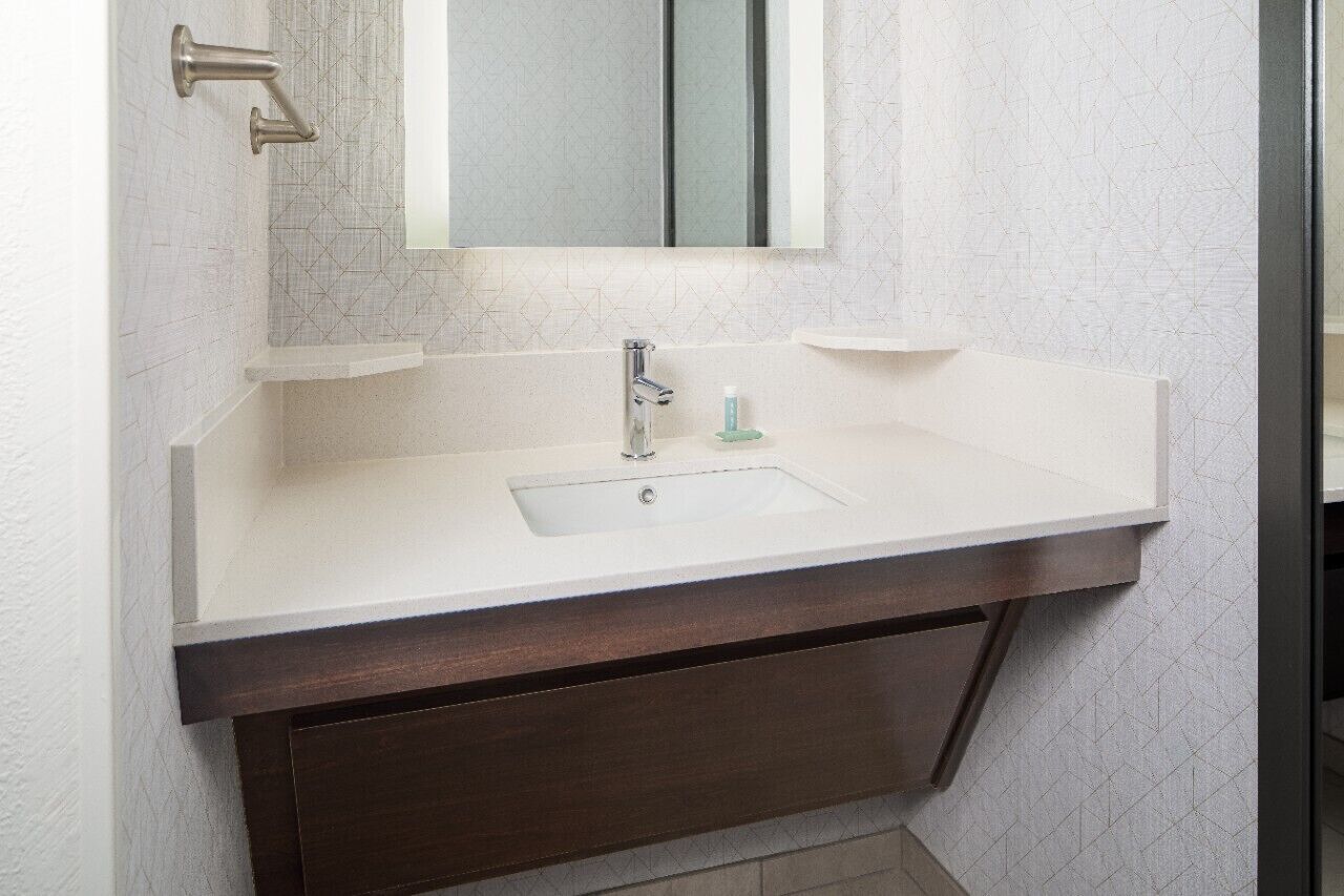 A bathroom with a white sink, a mirror, and a dark wooden vanity.