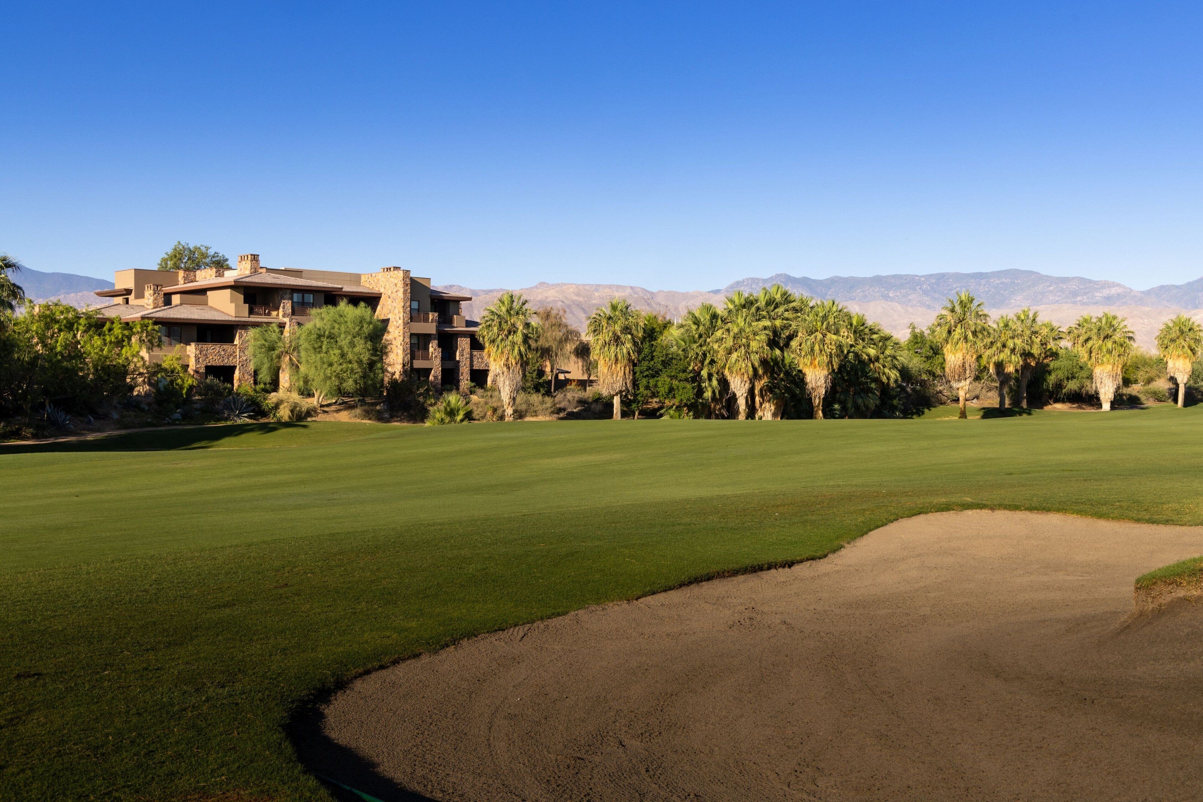 A golf course with a clubhouse and palm trees.