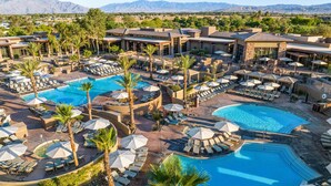 Een resort met meerdere zwembaden, ligbedden en parasols.