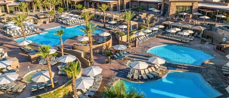 Un resort con varias piscinas, tumbonas y sombrillas.
