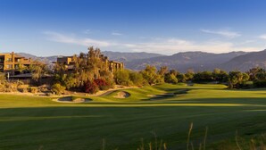 Ein Golfplatz mit Clubhaus, umgeben von Bergen und Bäumen.