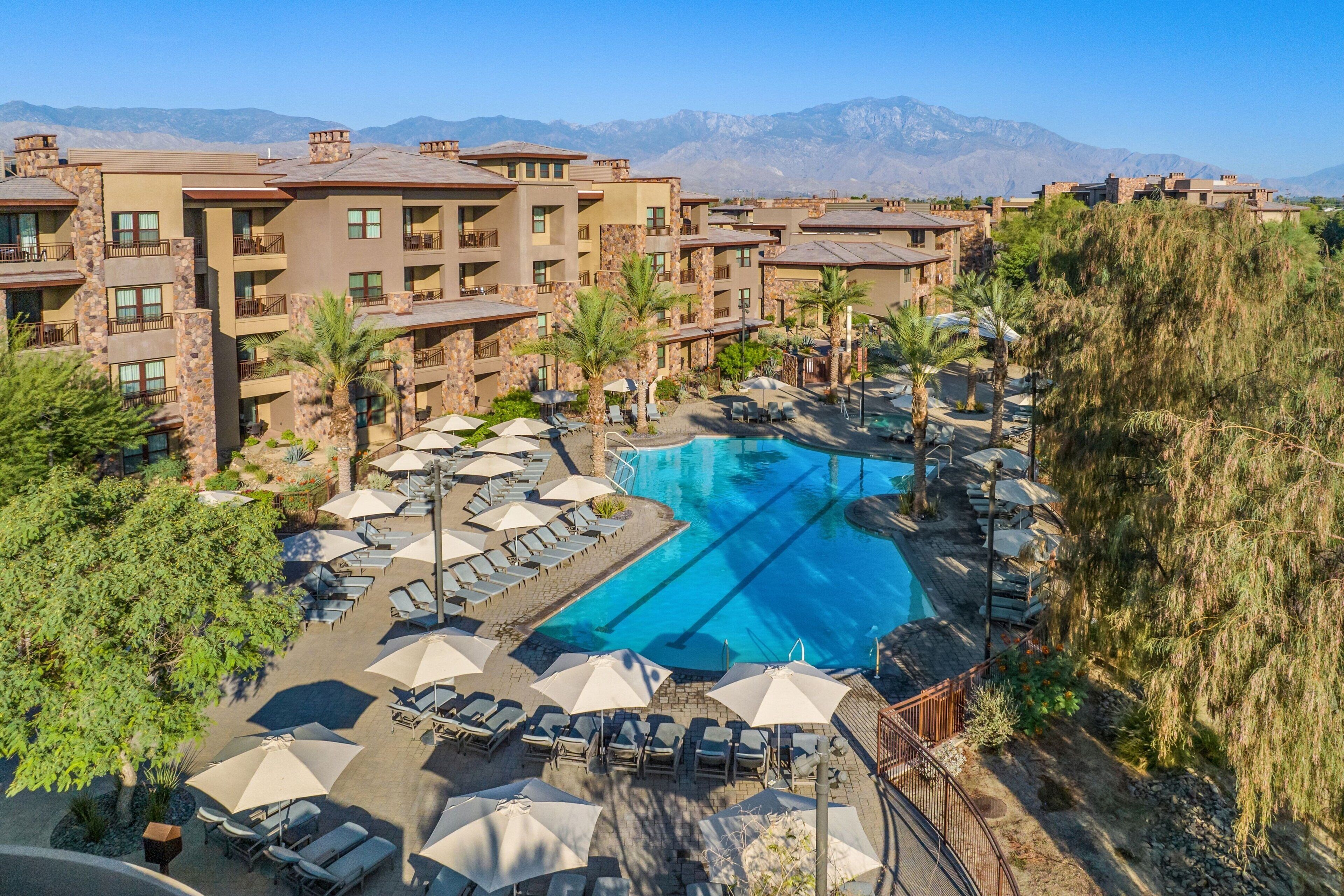 A resort with a swimming pool, lounge chairs, and umbrellas.