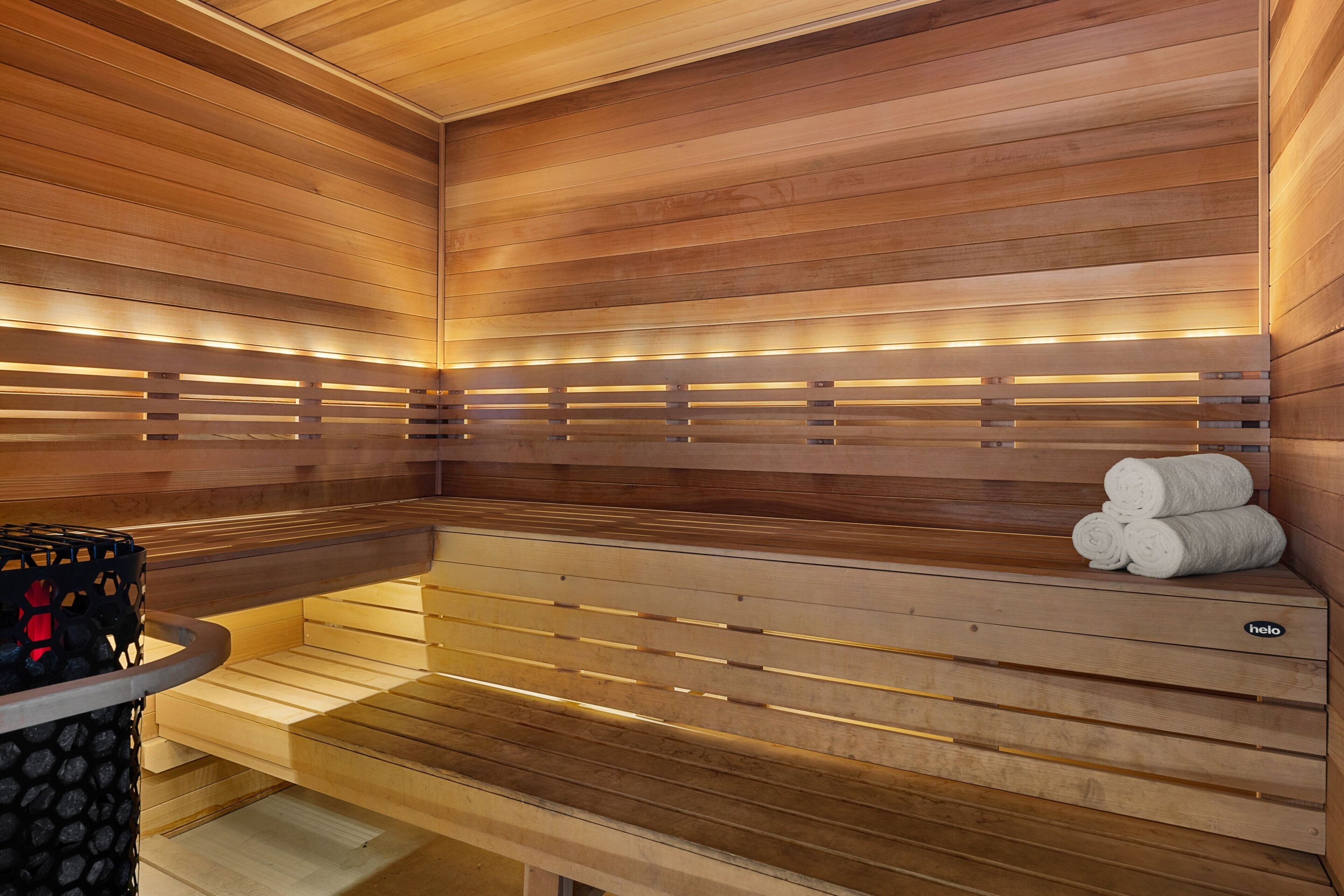 A sauna with wooden benches and a bench with towels.