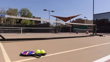 Un court de tennis avec un filet, une raquette de tennis et deux balles de tennis.