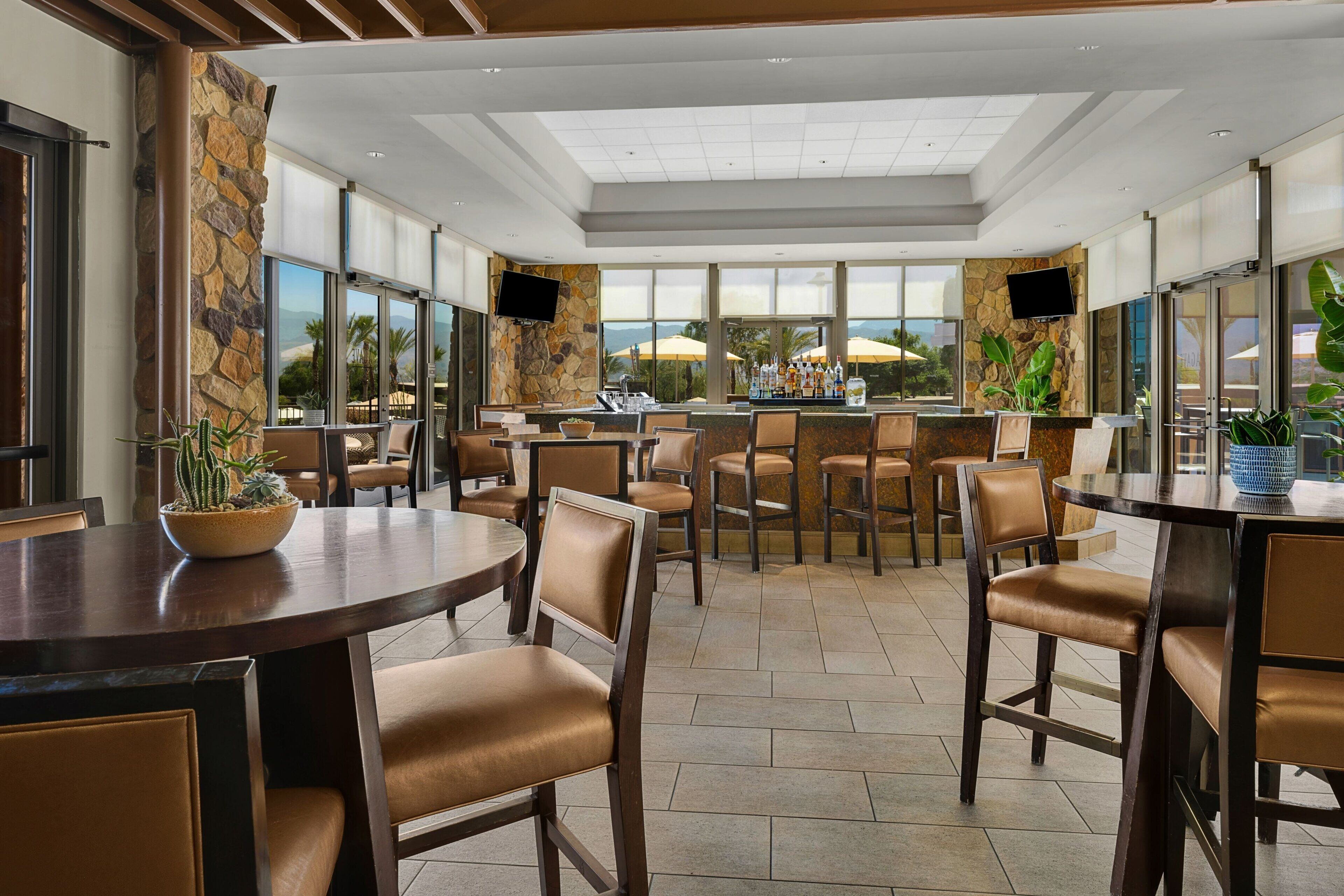 Eine moderne Bar mit Steindekoration, bequemen Sitzgelegenheiten und großen Fenstern, die einen Blick ins Freie ermöglichen.