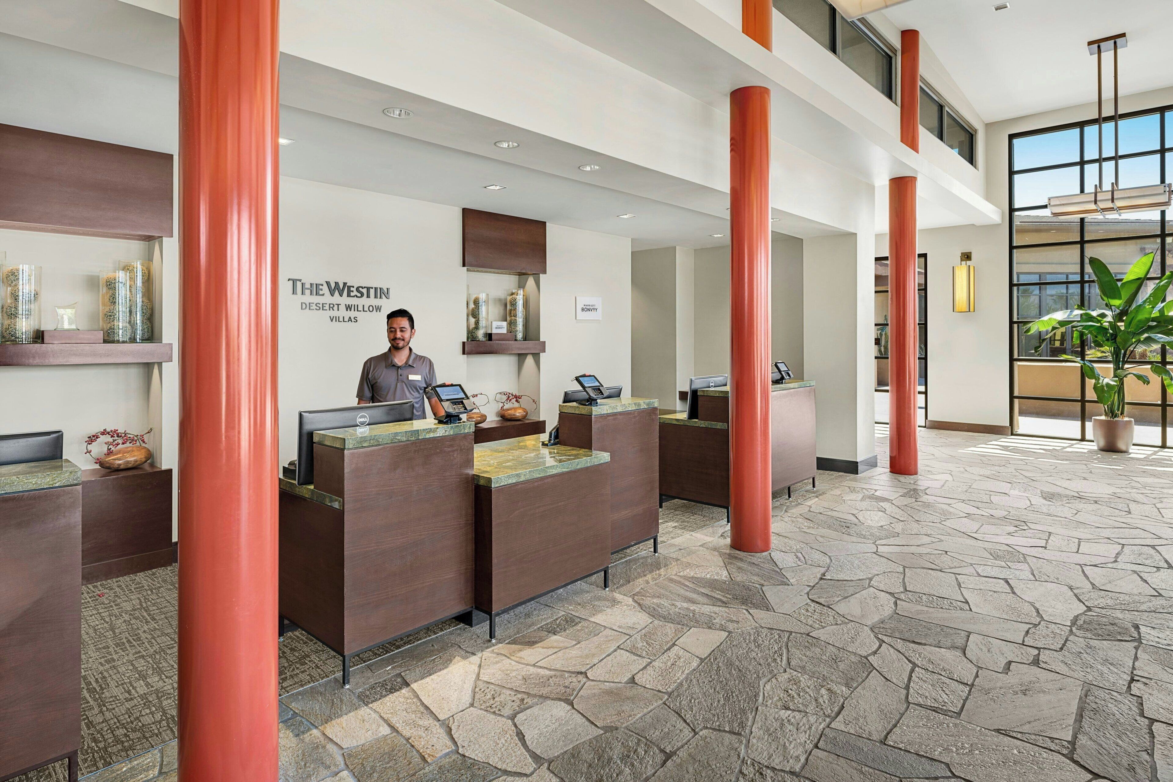 A reception area with a receptionist, multiple reception desks, and a stone-tiled floor.