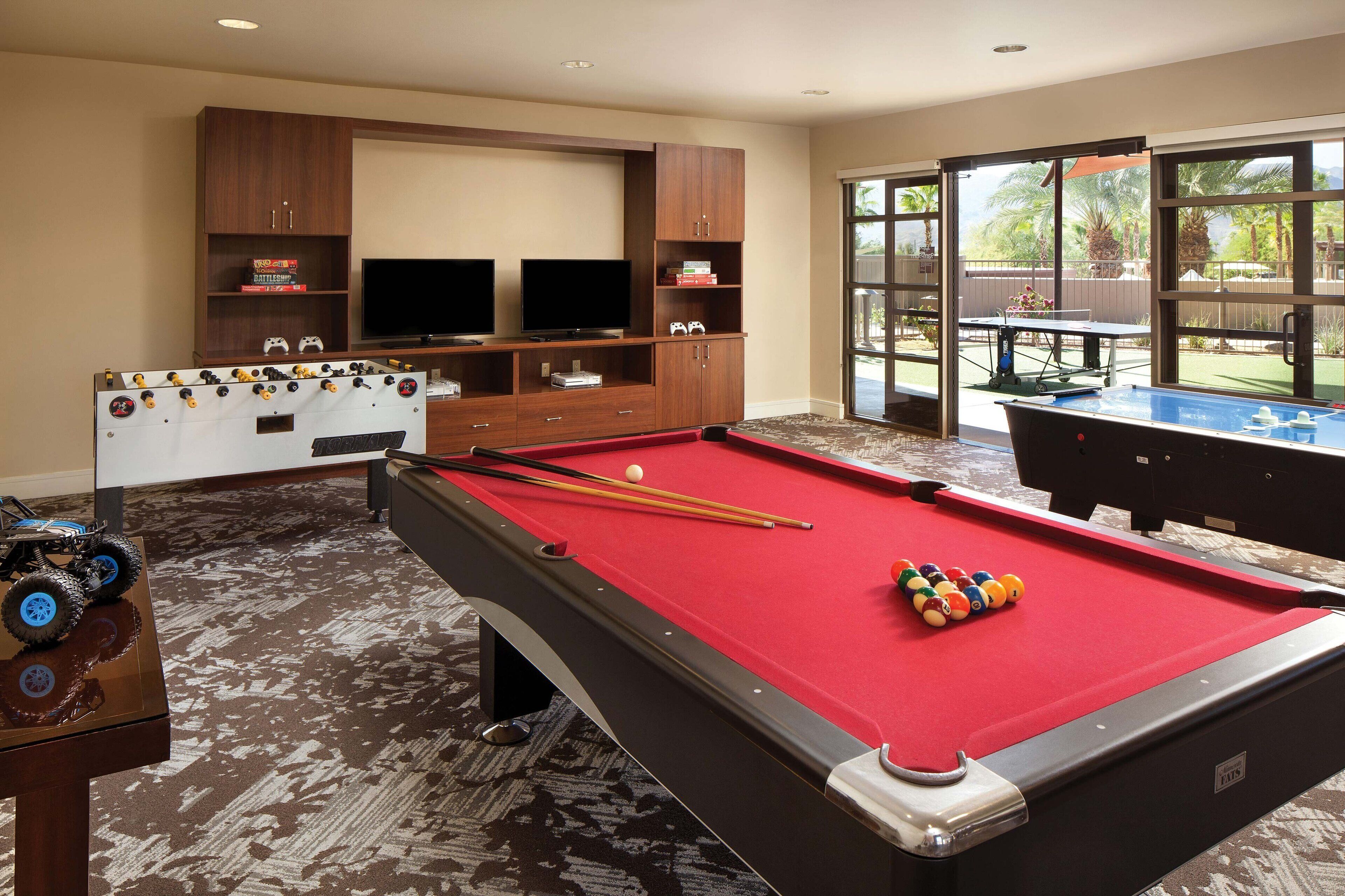 Une table de billard recouverte d’un drap de feutre rouge, une table de baby-foot et un jeu de billard.