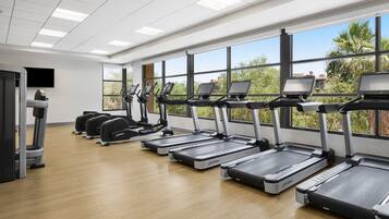 Un gimnasio con cintas de correr, bicicletas estáticas y una máquina de remo.