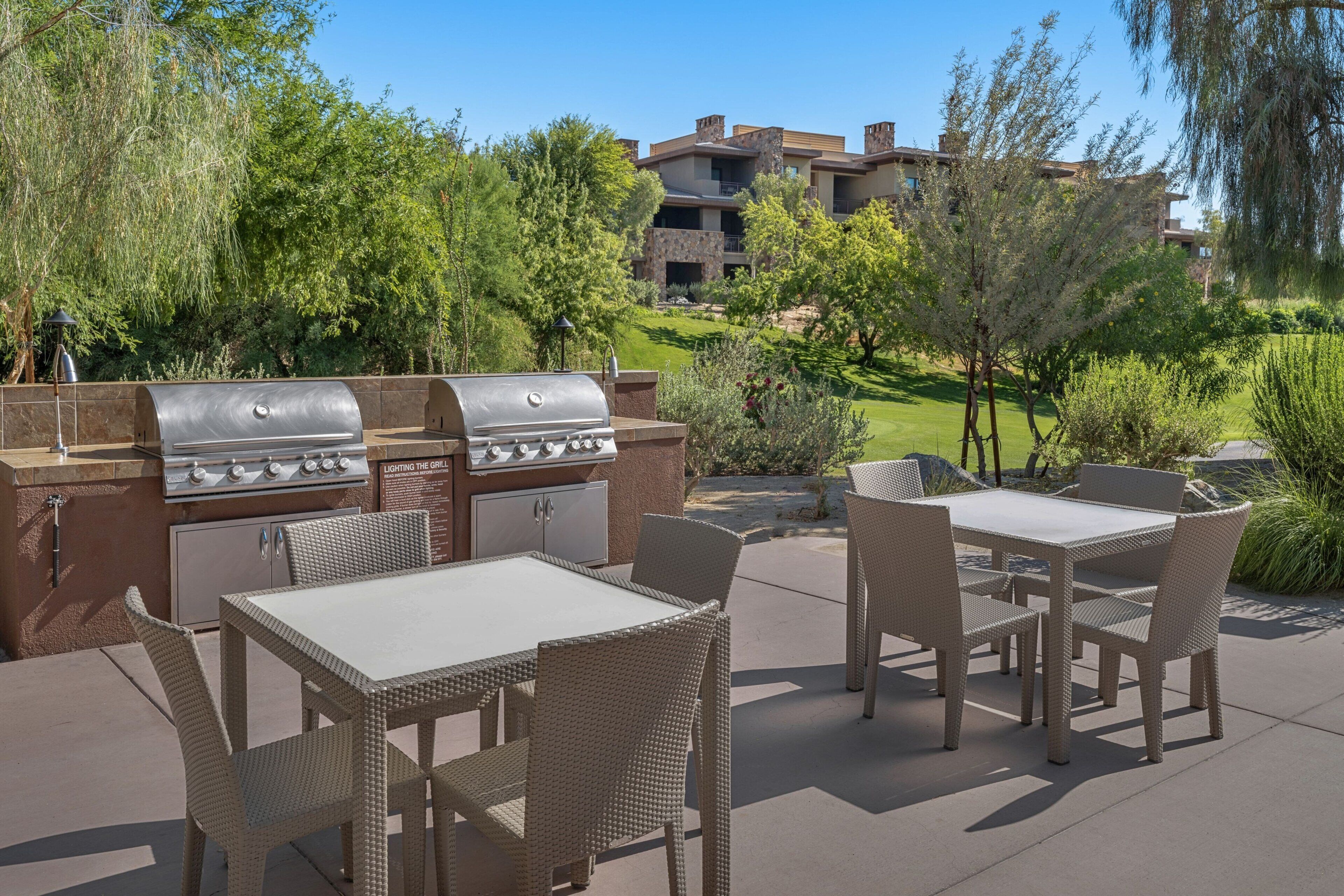 Une terrasse extérieure avec un barbecue, des chaises en osier et une table.