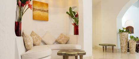 A modern interior with a white sofa, two round tables, and decorative vases.