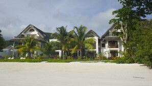 A beachfront property with multiple villas, each featuring a balcony and surrounded by lush greenery. - Village Du Pecheur (Praslin Island)