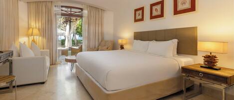 Una habitación de hotel con una cama grande, un sofá, una silla, una mesita y una lámpara.