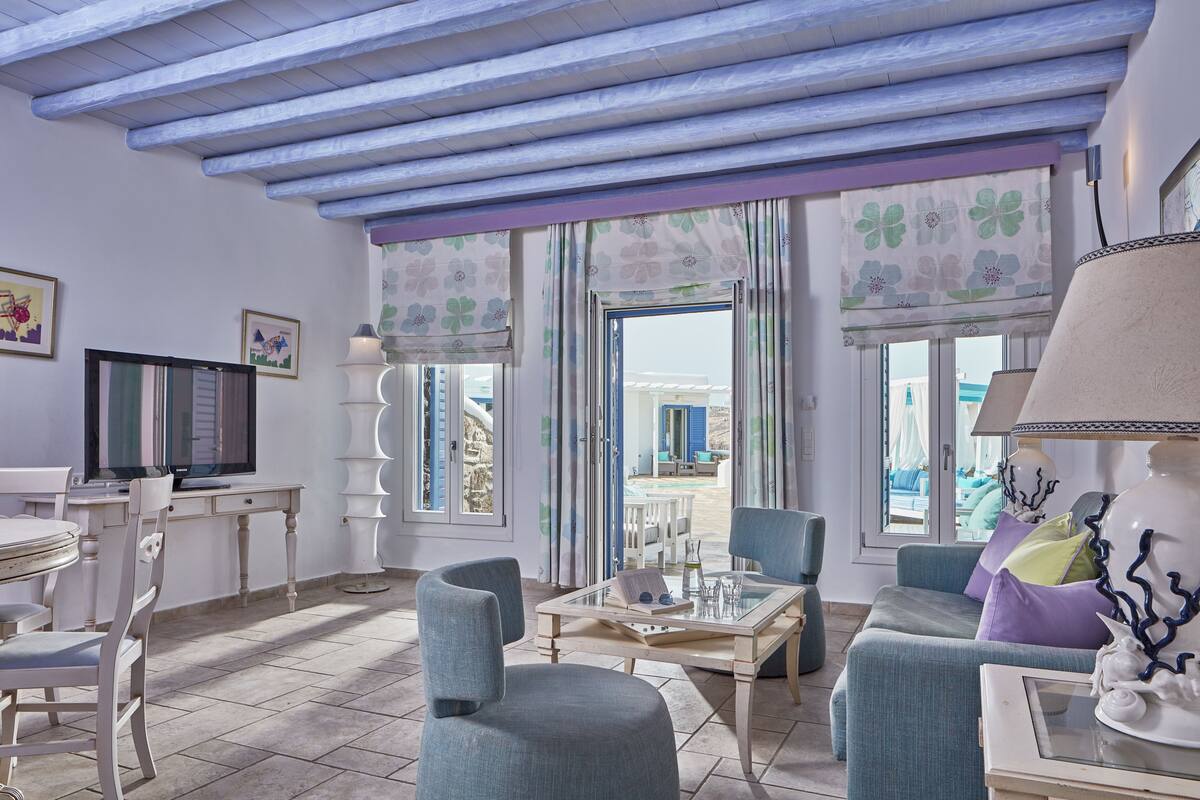 Un salon avec un téléviseur, une table à manger, des chaises et une vue sur la mer.