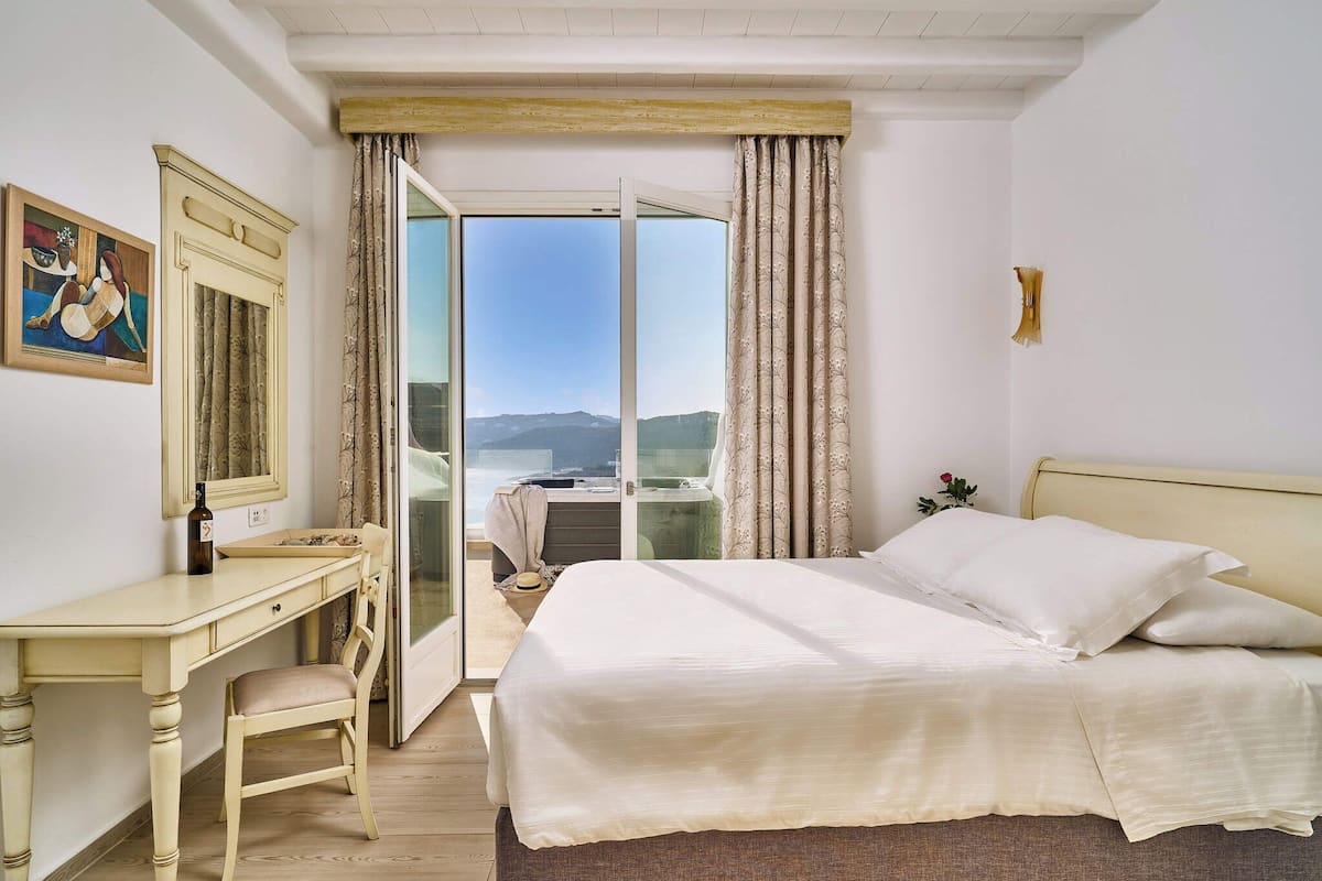 Une chambre à coucher avec un lit, un bureau et une chaise. Il y a un tableau au mur et une fenêtre avec des rideaux.