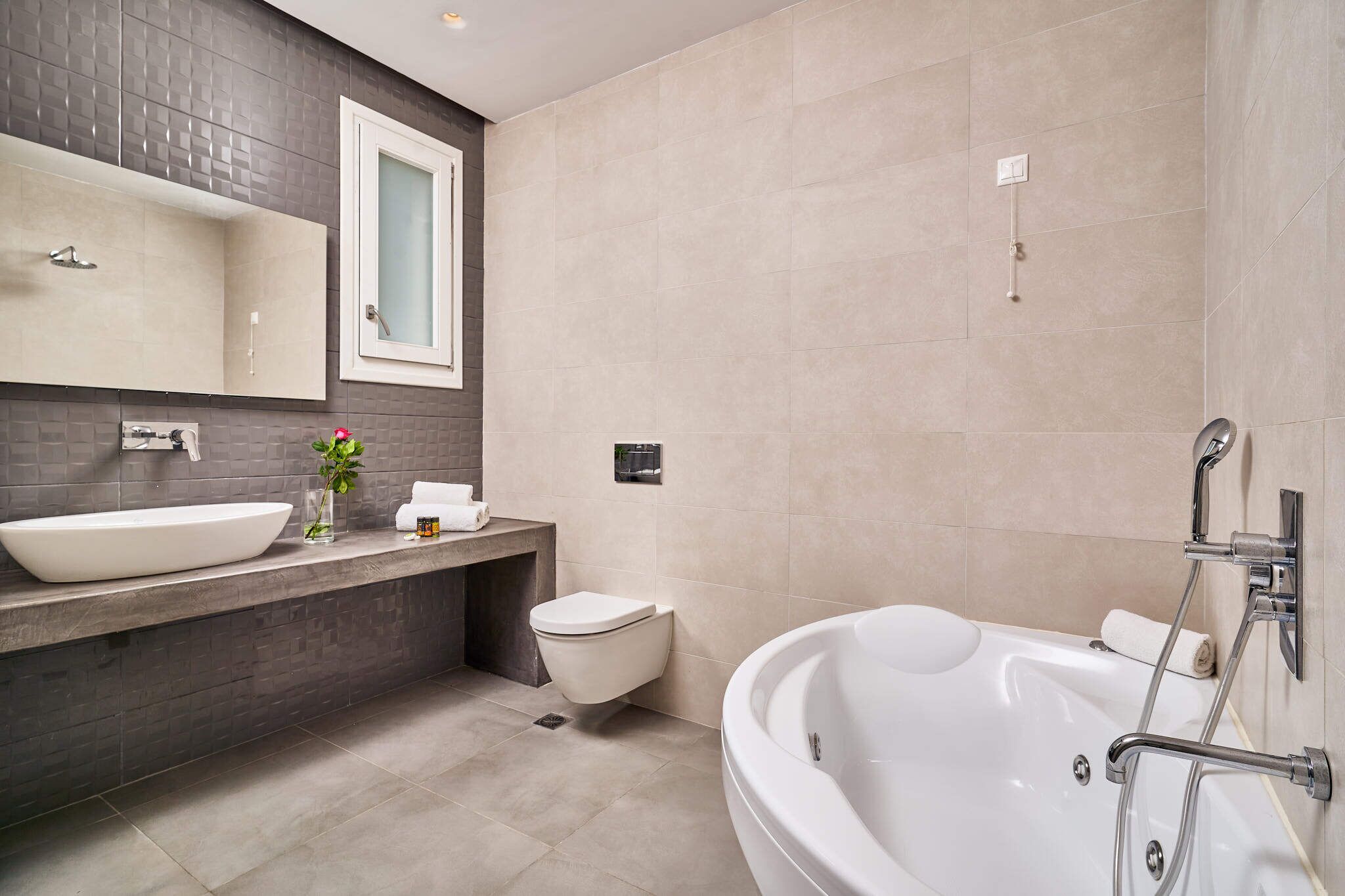 Ein modernes Badezimmer mit einer großen Badewanne, einem weißen Waschbecken und einer Toilette.