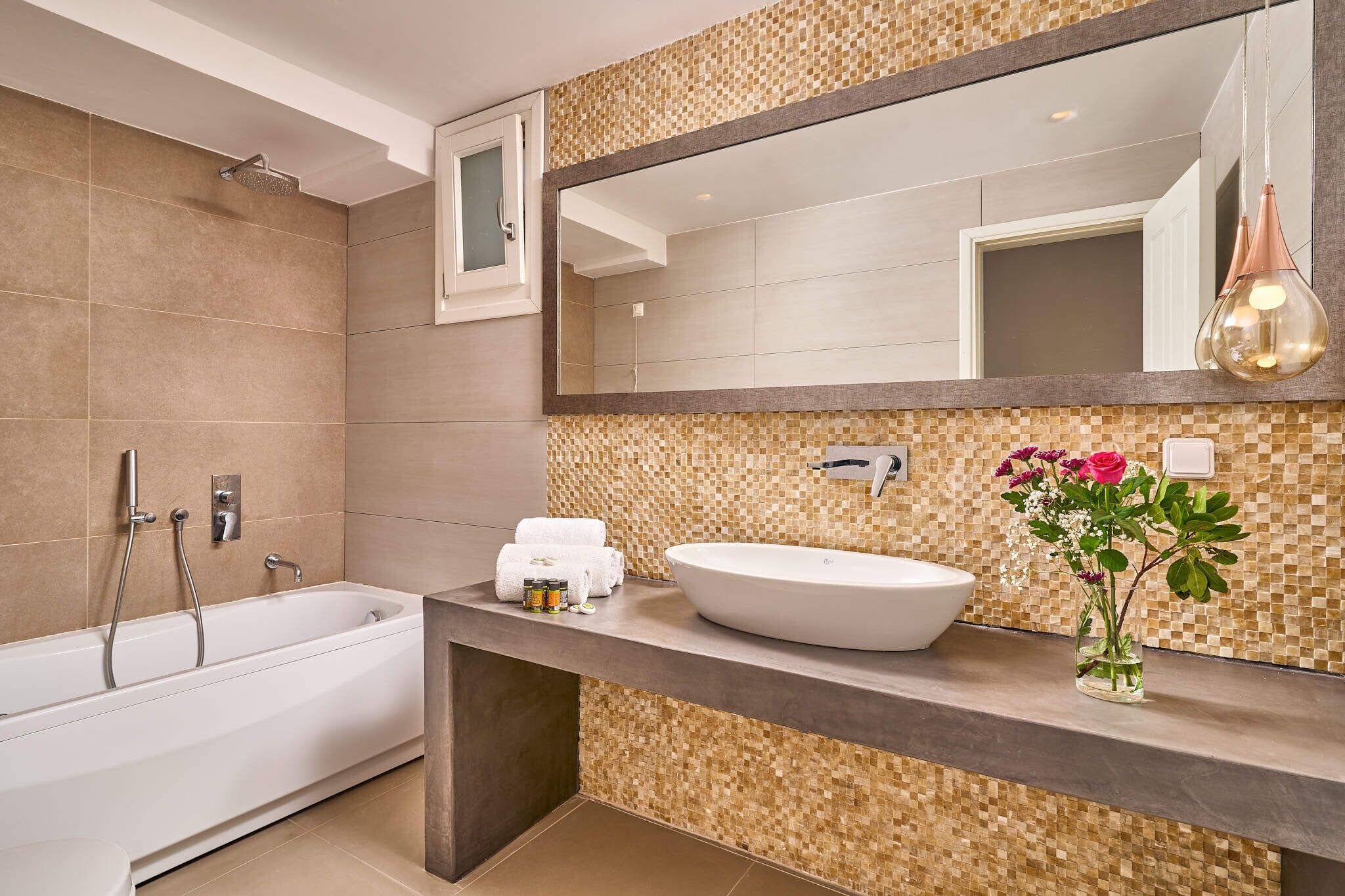 A modern bathroom with a freestanding bathtub, a large mirror, and a sink with a mosaic backsplash.
