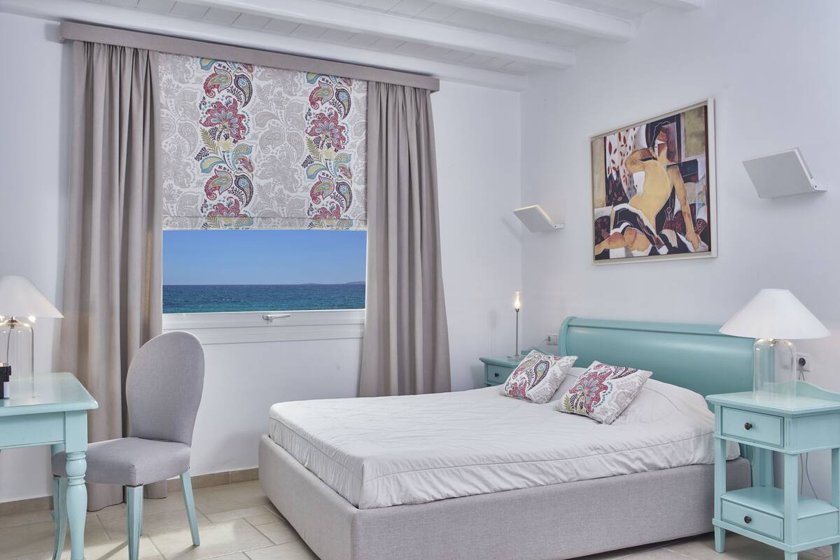 Une chambre à coucher comprenant un lit, une chaise, un bureau, une table de chevet et un tableau.