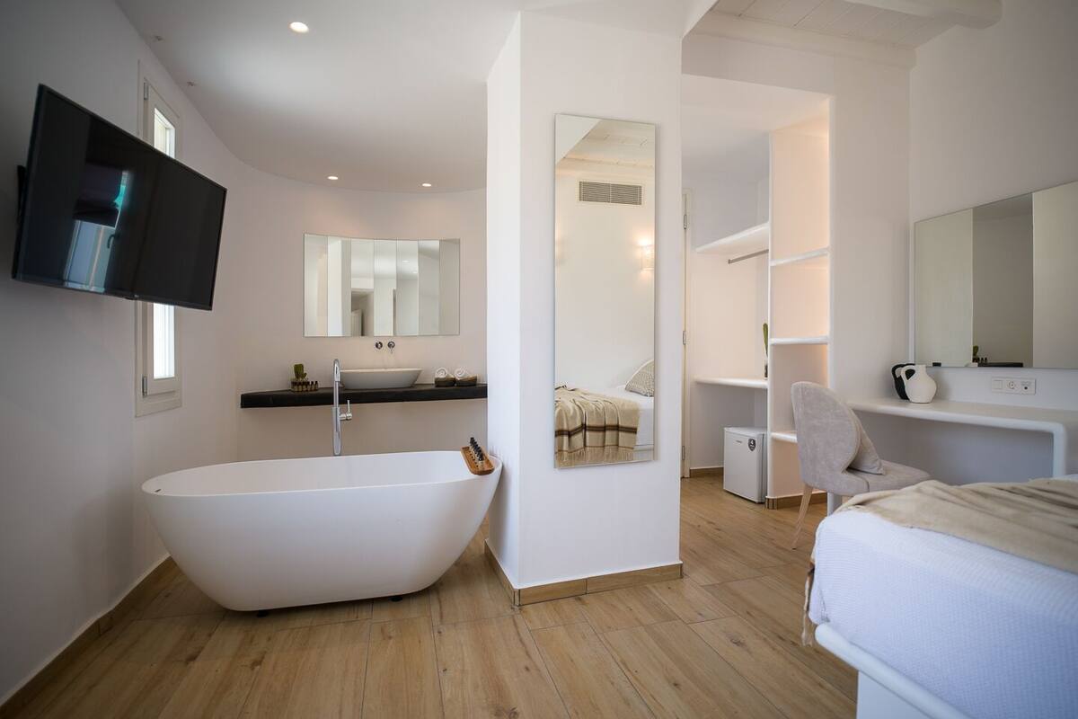 Une salle de bain moderne avec une baignoire sur pieds, un meuble-lavabo avec miroir et un dressing avec étagères.