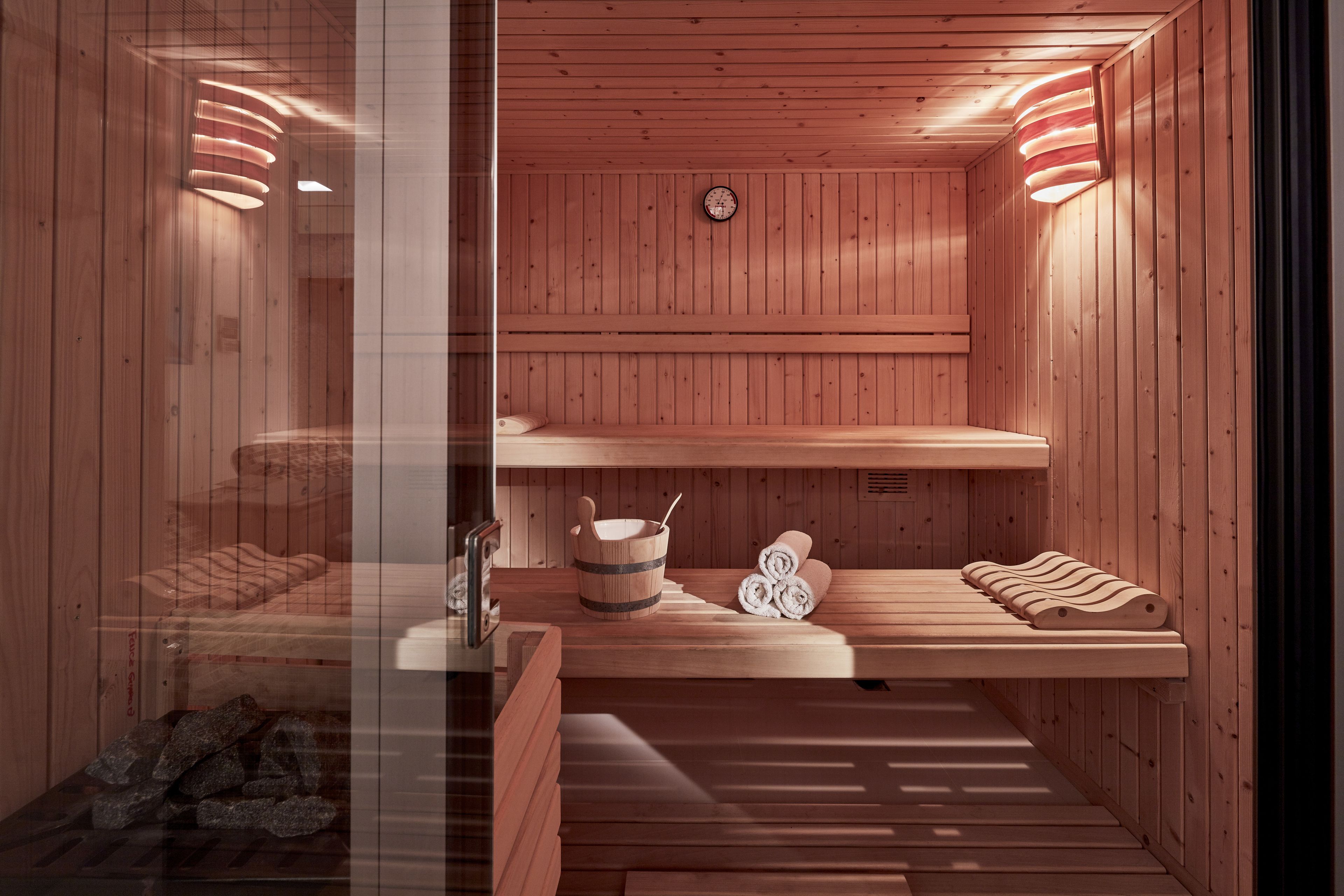 Eine Holzsauna mit Bänken, einem Eimer und Handtüchern.