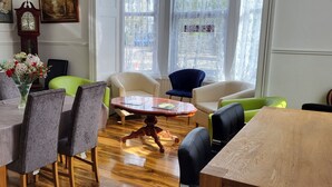 Een eetgedeelte met een houten tafel en stoelen, een ronde salontafel, en een klok aan de muur.