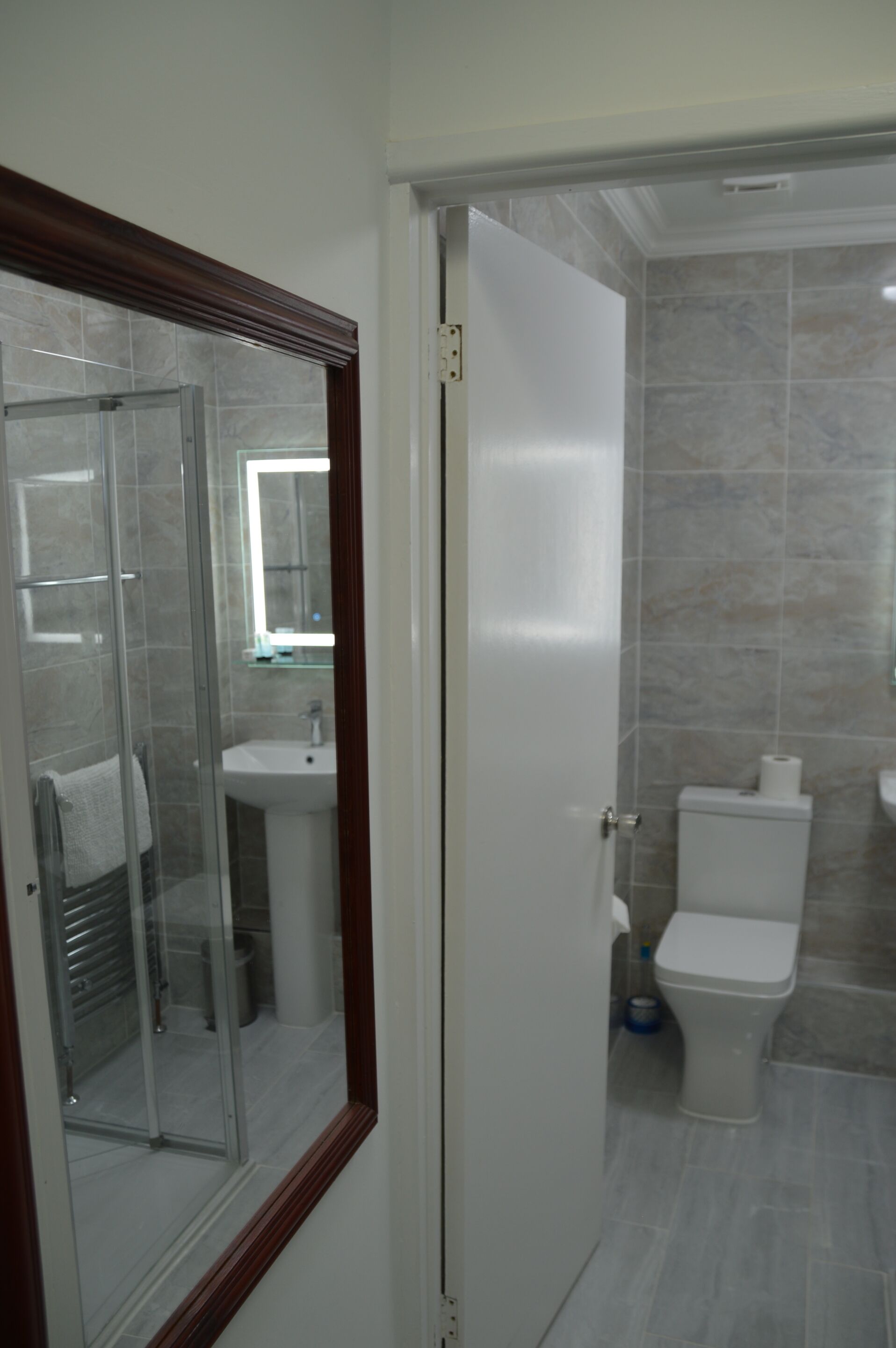 Un baño con cabina de ducha de vidrio, lavamanos e inodoro.