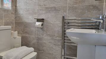 Un baño moderno con inodoro, lavamanos y toallero.