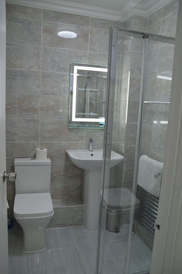 Un baño con inodoro, lavamanos y cabina de ducha de vidrio.