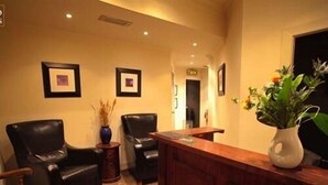 A reception area with a wooden desk, two black leather chairs, and a vase with flowers. - Rab Ha's (Glasgow)