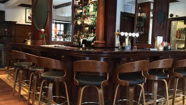 A bar area with wooden bar stools and a well-stocked liquor shelf. - Rab Ha's (Glasgow)