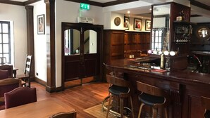 A bar area with wooden flooring, bar stools, and a counter with a mirror and various bottles. - Rab Ha's (Glasgow)