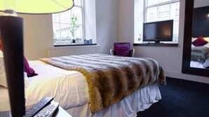 A hotel room with a bed, a chair, a TV, and a lamp. - Rab Ha's (Glasgow)