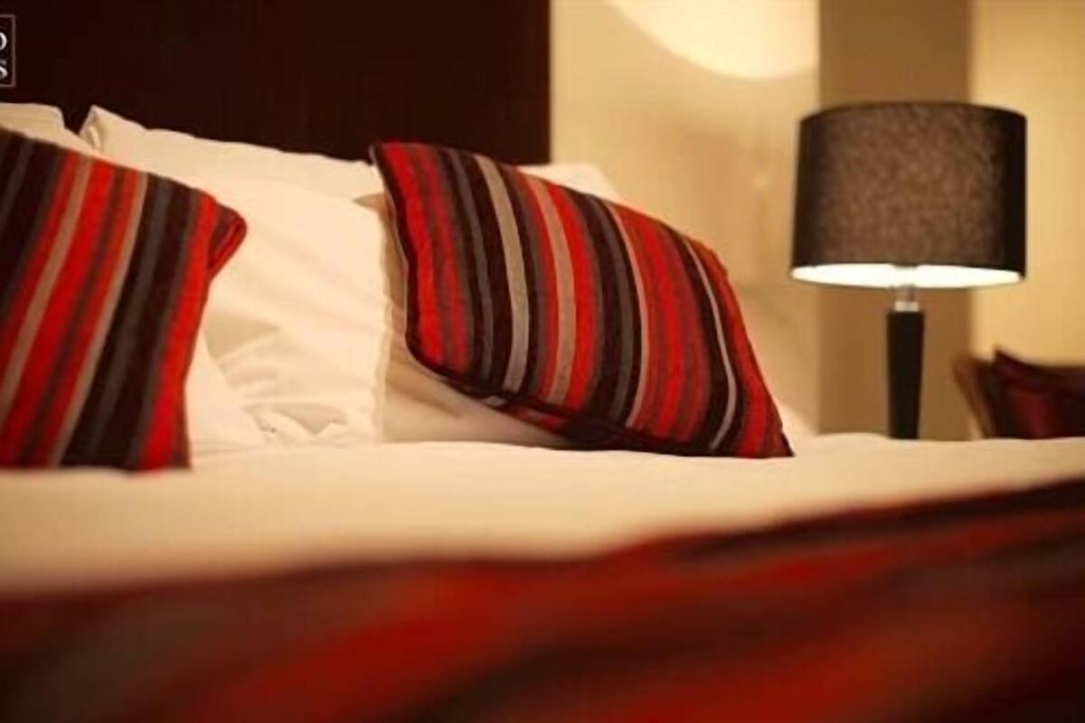 A bed with striped pillows and a lamp beside it.