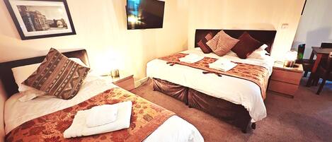 A hotel room with two beds, a flat-screen TV, a framed picture on the wall, and a desk with a chair.