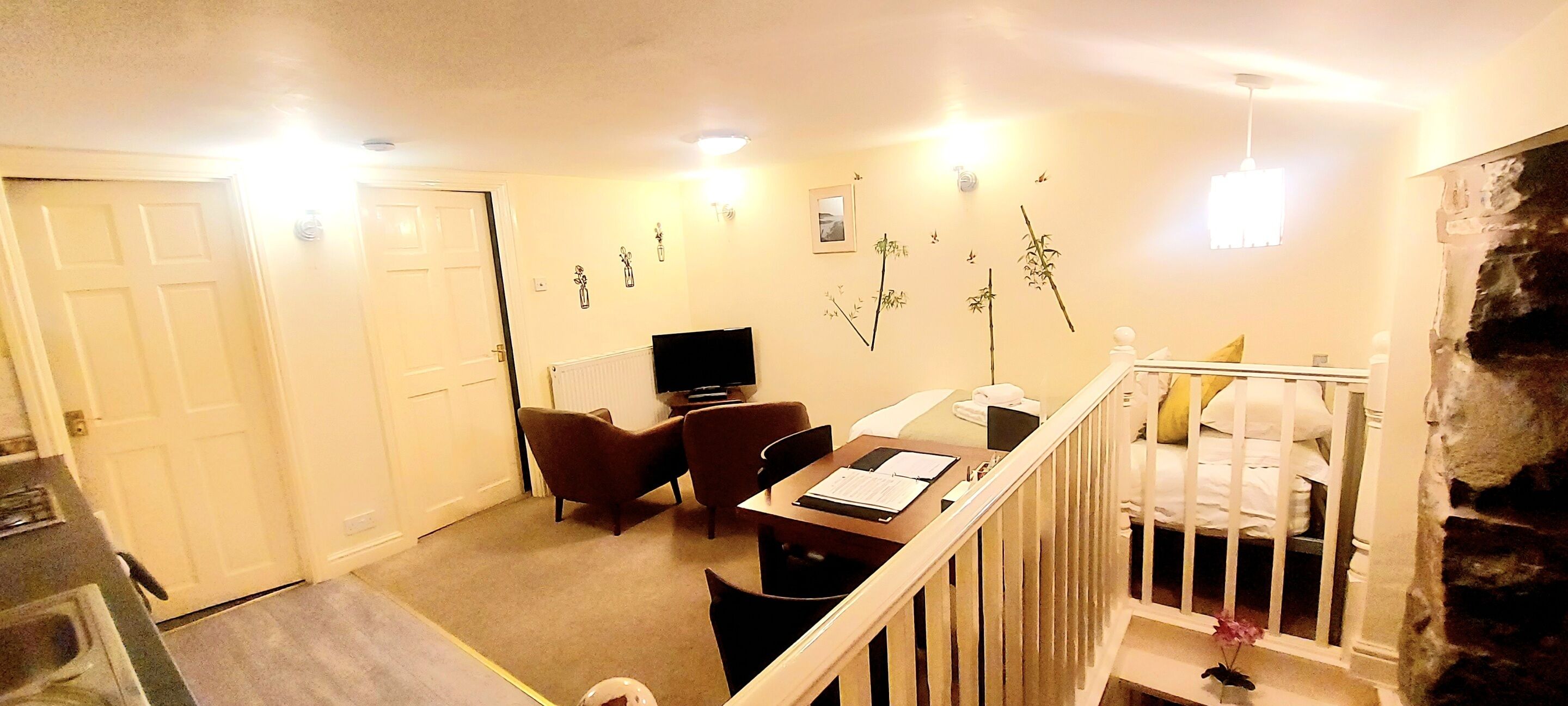 A room with a bed, a desk, a chair, a television, and a staircase.