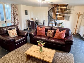 Ein Wohnzimmer mit zwei Ledersofas, einem Holztisch und einer Treppe.