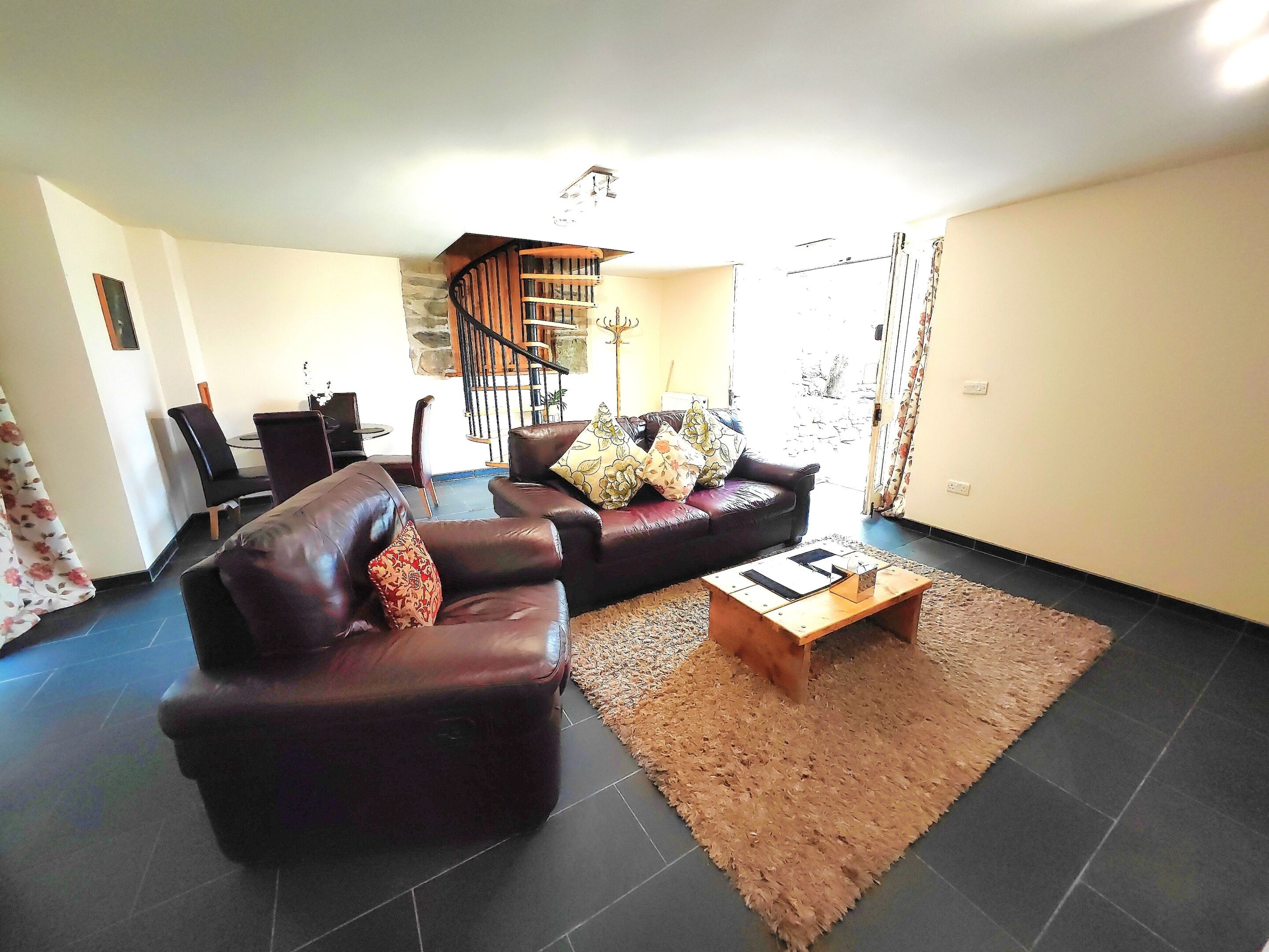 A living room with two leather sofas, a wooden coffee table, and a staircase leading to an upper floor.