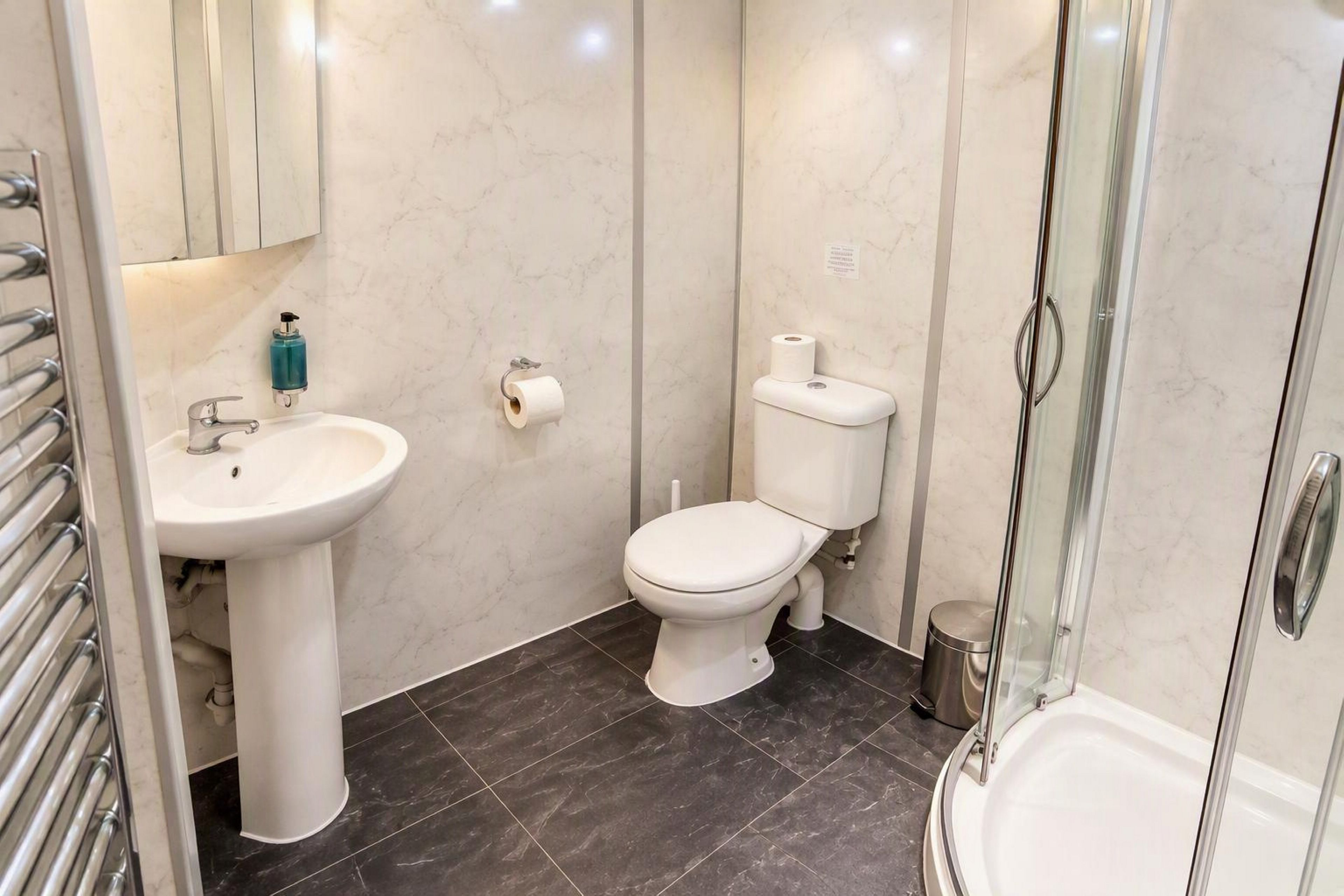 Ein Badezimmer mit Waschbecken, Toilette und Duschkabine aus Glas.