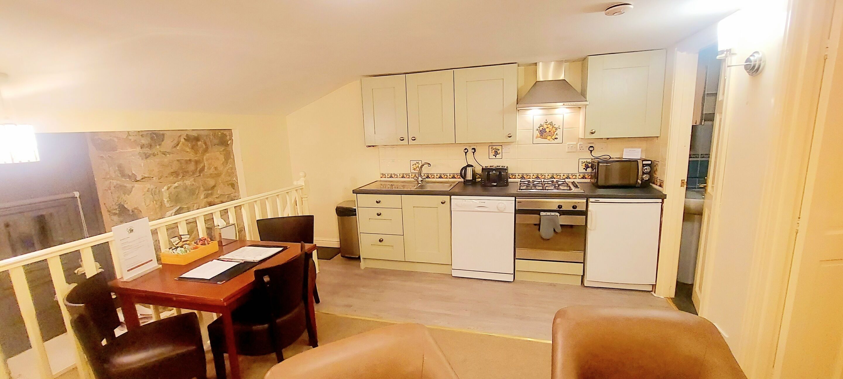A compact kitchen with white cabinets, a dining table with chairs, and a small seating area.
