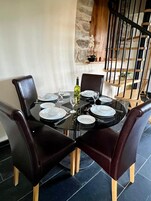 A dining table with six chairs, a bottle of wine, and plates set for a meal.