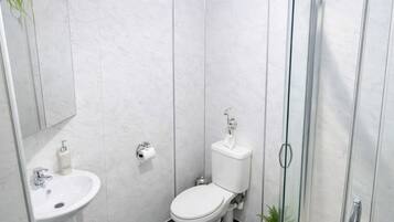Un baño moderno con inodoro, lavamanos y cabina de ducha de cristal.