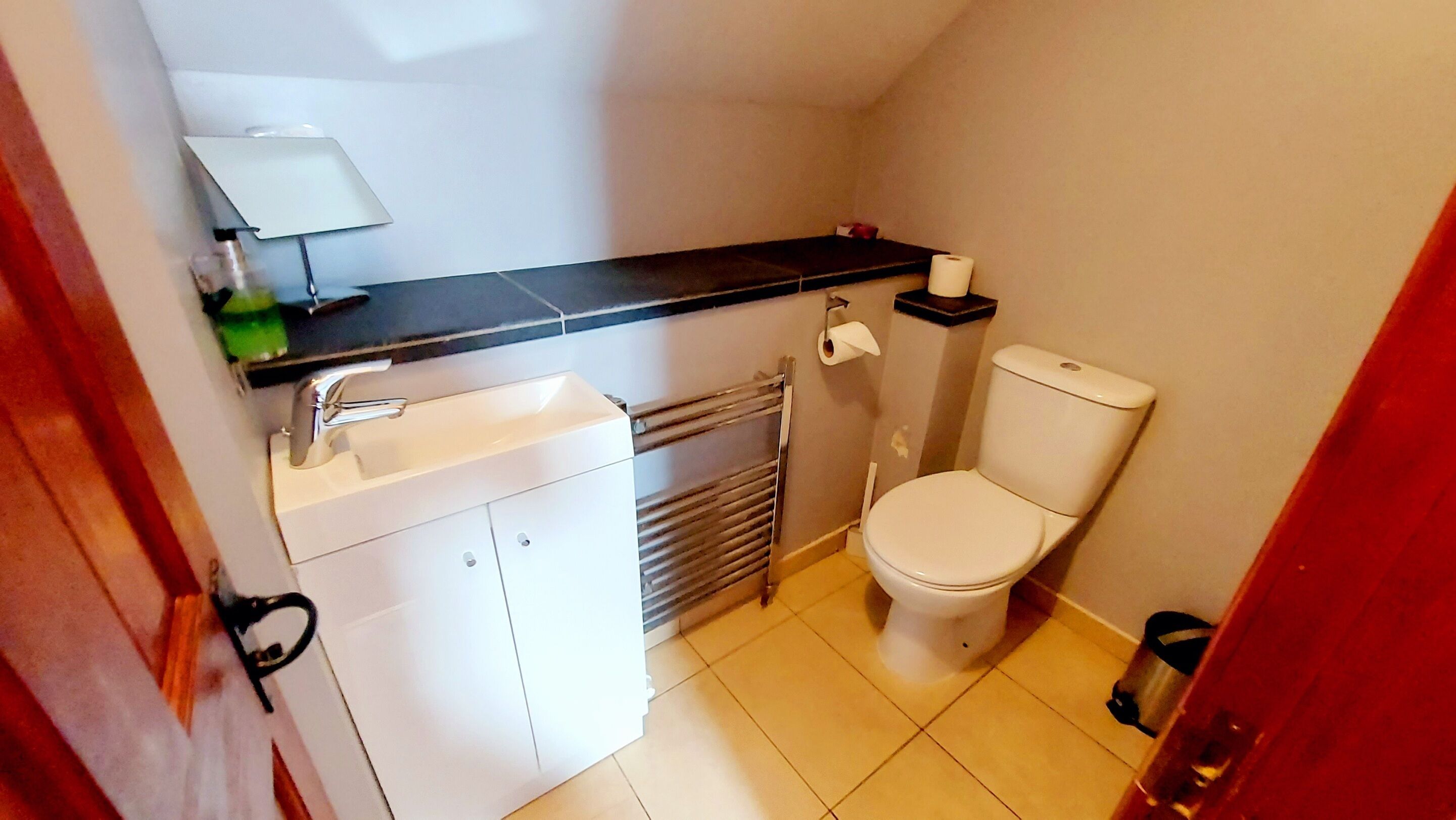 Ein kleines Badezimmer mit Toilette, Waschbecken und Handtuchhalter.