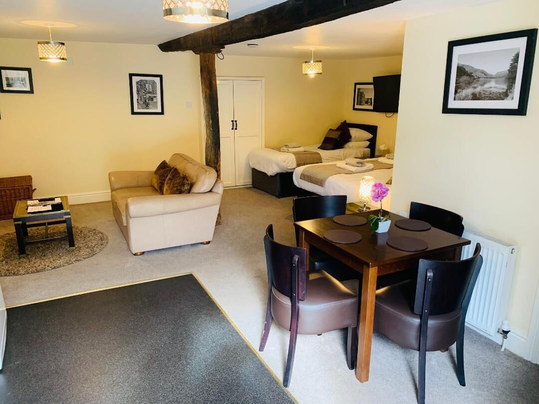 Una sala acogedora con un sofá, una mesa de comedor con sillas y una cama con dos almohadas.