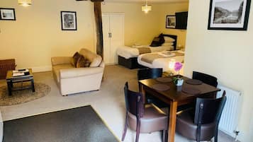 Una sala acogedora con un sofá, una mesa de comedor con sillas y una cama con dos almohadas.
