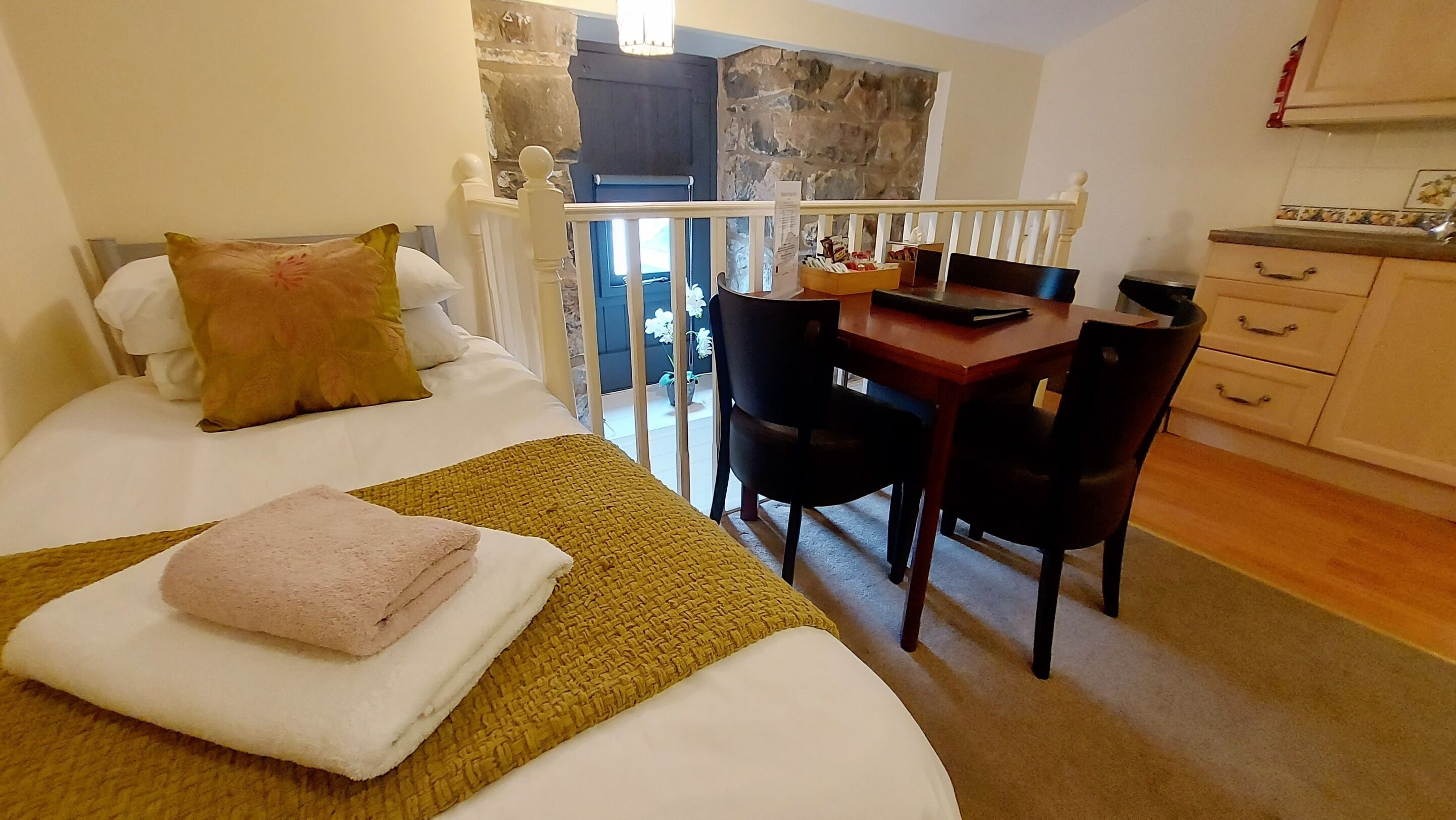 Un dormitorio con cama, escritorio y silla. Cuenta con un balcón con vistas al exterior.