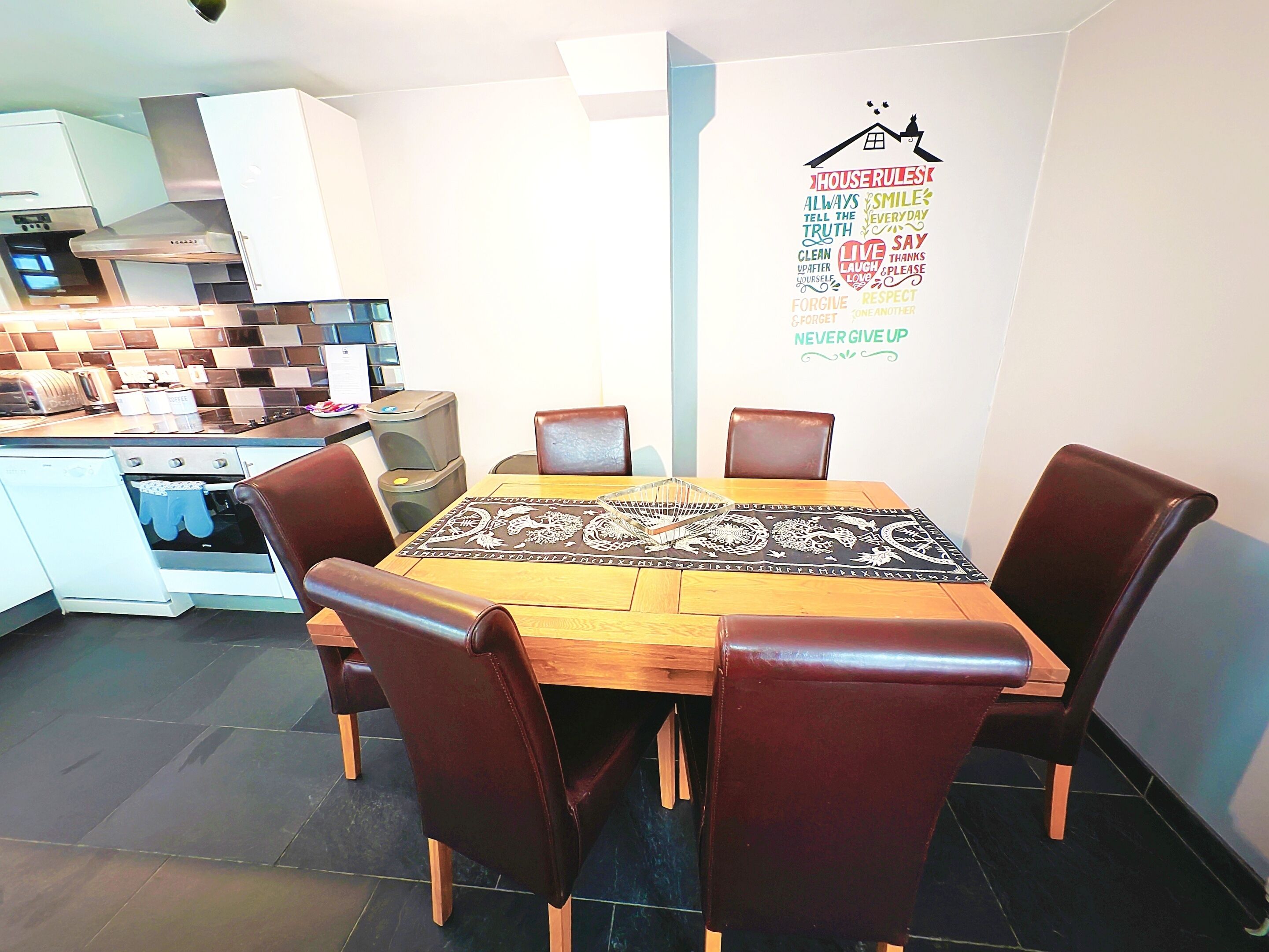 Una cocina moderna con comedor, que presenta una mesa de madera, sillas de cuero y una isla de cocina.