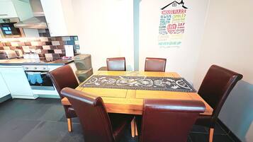 Una cocina moderna con comedor, que presenta una mesa de madera, sillas de cuero y una isla de cocina.