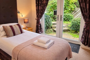 A bedroom with a bed, a bedside lamp, and curtains. - Dolgun Uchaf Guesthouse (Dolgellau)