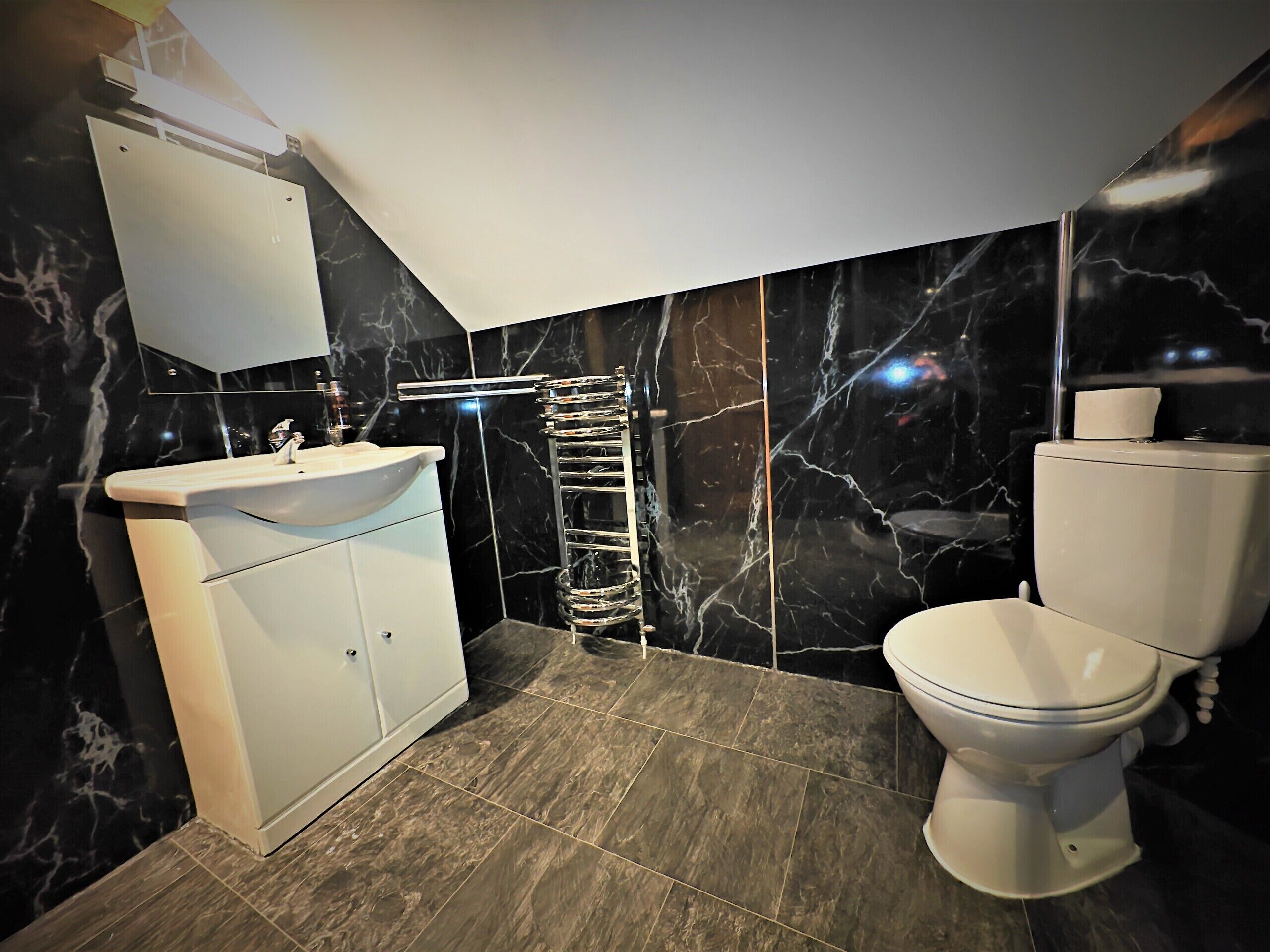 Une salle de bain moderne avec un lavabo blanc, des toilettes et un porte-serviettes.
